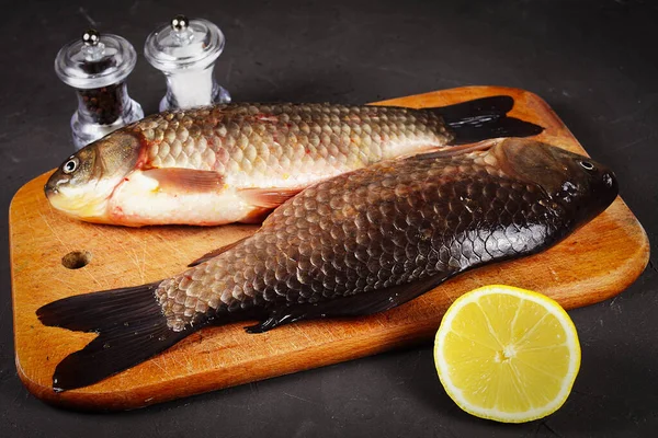 2匹の新鮮なクリスチャンの鯉がまな板の上に横たわっていますレモン塩コショウ用のミルビネット — ストック写真