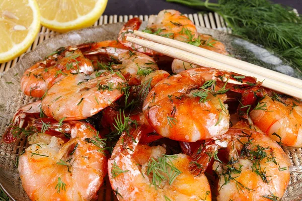 Bambu hasırının üstünde kızarmış kral karidesleri, limon, dereotu, yakın plan.