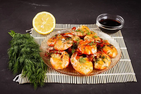 Bambu hasırının üstünde kızarmış kral karidesleri, limon, dereotu, yakın plan.