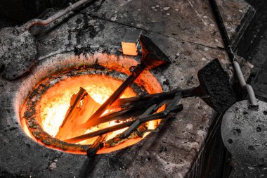 Bir dökümhane atölyesinde. Bronz metal çubuklar bir potada eritilir.