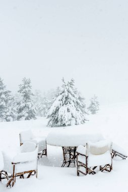 Bir kar fırtınası altında restoran masaları ve sandalyeler