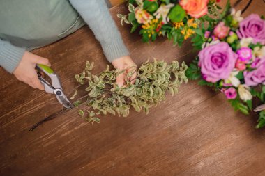 Çiçekçi kız hediye kutusunda buket paketliyor. Küçük işletme kavramı. Üst görünüm