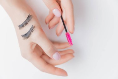 Eller kız kirpik uzatıcısı beyaz arka plan, üst görünüm. Güzellik konsepti