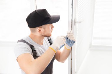 İnşaat işçisi eve plastik beyaz upvc pencereler kurmak için tornavida kullanır