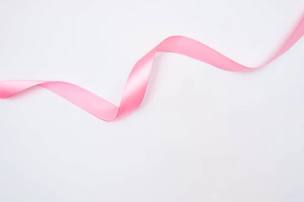 Закручена рожева стрічка з підсвічуванням ізольована на білому тлі, вид зверху — стокове фото