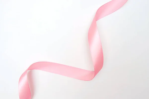 Загнутая розовая лента с выделенными бликами на белом фоне, вид сверху — стоковое фото