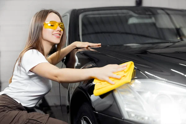 Hand worker girl lucida e pulisce i fari in microfibra su auto nera. Concetto servizio di lavaggio auto — Foto Stock