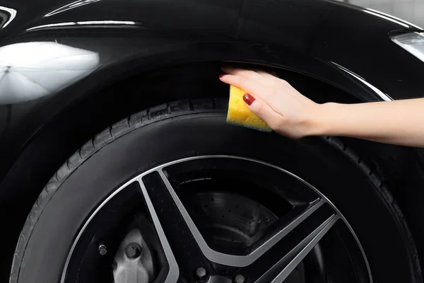 Araba yıkama servisi, siyah lastikleri silmek için sprey ve sünger kullanın. — Stok fotoğraf
