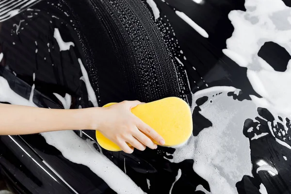 Esponja de mano de fondo sobre coche negro para lavar espuma blanca. Vista superior —  Fotos de Stock