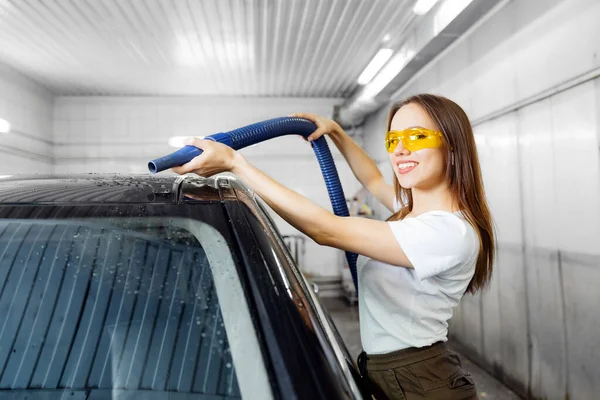 Chica trabajadora utiliza secador turbo para eliminar las gotas de agua. Servicio de lavado de coches express — Foto de Stock