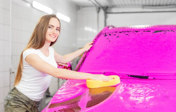 Chica trabajadora con esponja amarilla lavado de coche de espuma rosa —  Fotos de Stock