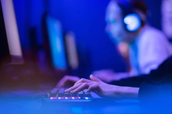 Profesional jugador en línea dedos de la mano teclado mecánico en neón color borroso fondo. Enfoque suave, vista trasera — Foto de Stock