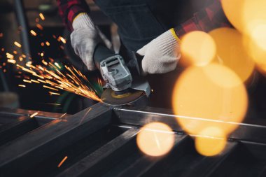 Açı öğütücüyle çalışan kadın kıvılcım ile kaynak yaptıktan sonra metali keser ve parlatır.