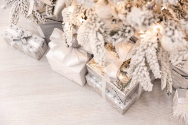 Yeni yıl ağacının altında suni kar ve altın ışıklı Noel hediyeleri. Gümüş rengi