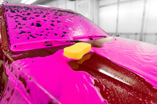 Concepto de lavado de autos de mujer. Esponja amarilla se encuentra en espuma rosa suciedad limpia — Foto de Stock