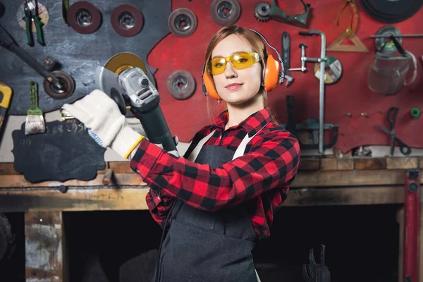 Joven hembra que trabaja con la máquina amoladora pule el metal después de soldar con chispa — Foto de Stock