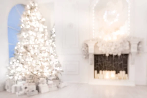 Zamazane tło Bożonarodzeniowe wnętrze z drzewem noworocznym i sztucznym kominkiem ozdobionym światłem na wakacje, kolor biały — Zdjęcie stockowe