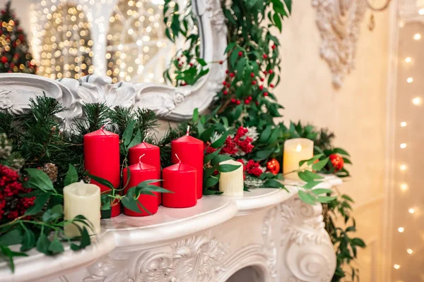 Kerstversiering rode waskaarsen op witte open haard — Stockfoto