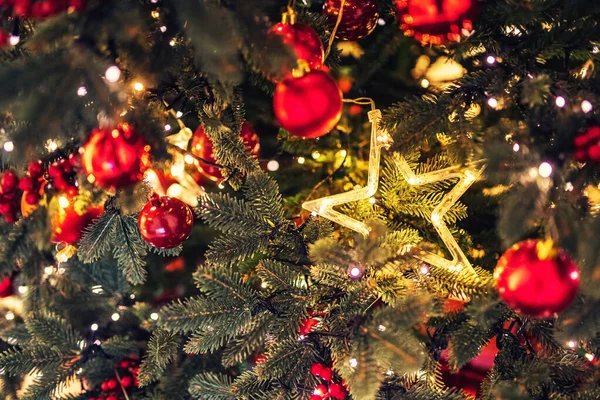 Boże Narodzenie tło drzewo Nowy rok gałąź z dekoracjami czerwone kulki prezenty i gwiazda, z bokeh światło — Zdjęcie stockowe