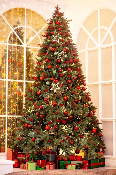 Різдвяний фон гілка сосни з прикрасами червоні кульки подарунки та зірка, з боке світло — стокове фото