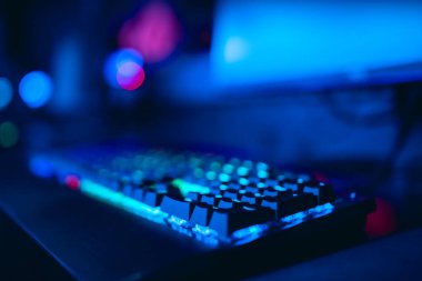 Bulanık arka plan bilgisayarı, klavye, mavi ve kırmızı ışıklar. Turnuvalarda oynayan oyuncuların konsept esports arenası