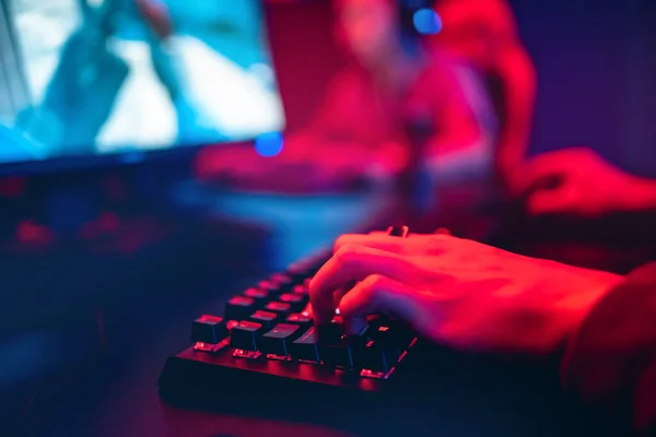 Profesional jugador en línea dedos de la mano teclado mecánico en neón color borroso fondo. Enfoque suave, vista trasera —  Fotos de Stock