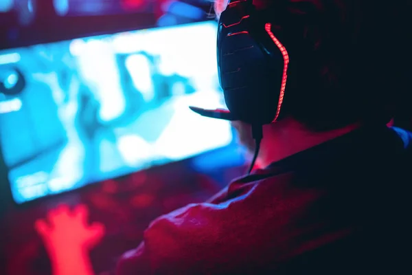 Fondo borroso jugador profesional jugando torneos juegos en línea ordenador con auriculares, rojo y azul — Foto de Stock