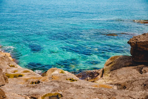 Blauw smaragd zeewater met groot stenen strand. Rotsachtige kust transparant turquoise bodem Malta — Stockfoto