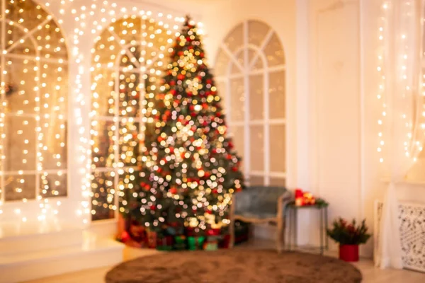 Verschwommene Hintergrundbeleuchtung Weihnachtsinterieur mit Neujahrsbaum und Geschenken in roten, grünen Farben — Stockfoto