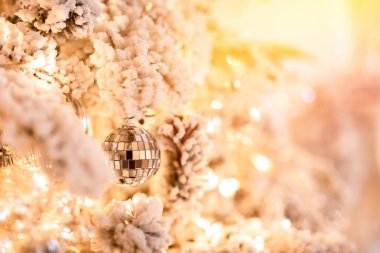 Noel ağacı arka planında yapay karla süslenmiş oyuncak topları, dallı altın aydınlatma