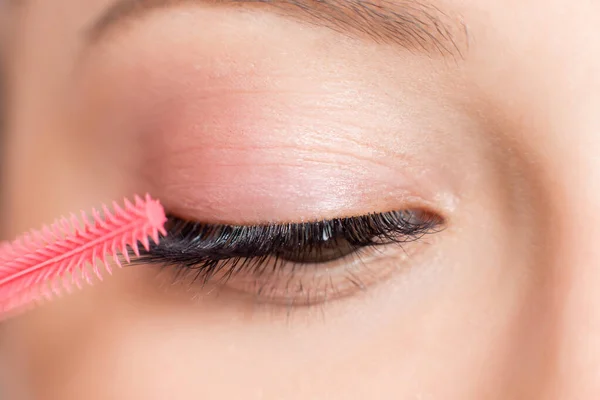 Eyelash extension procedure. Woman master combs lashes