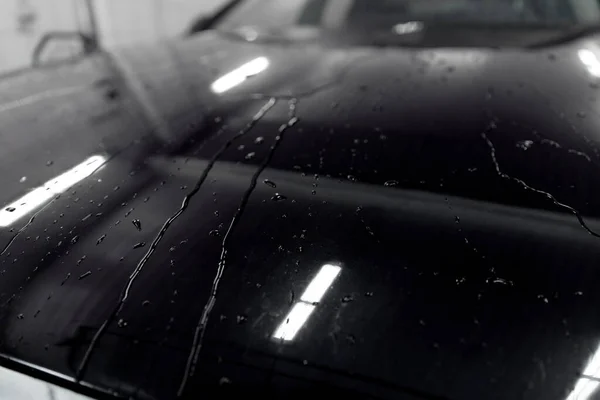 Gotas de agua en la capucha del coche negro después del lavado — Foto de Stock