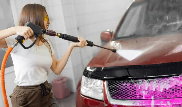 Servicio de lavado de autos. Mujer trabajadora limpiando auto usando agua de alta presión — Foto de Stock