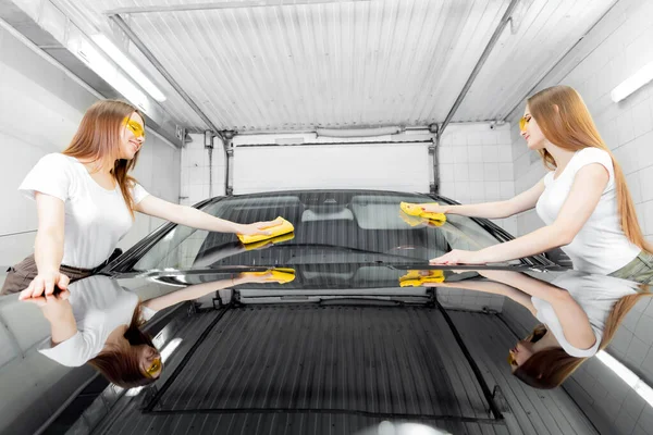 Two beautiful women worker washing windshield with sponge on car wash, window polishing — Stock Photo, Image