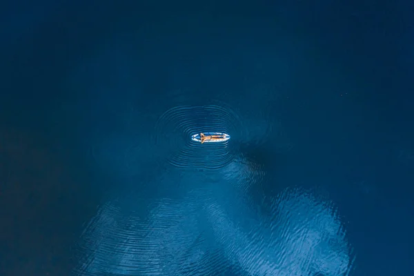 男はボード上の青い海の水の上にリラックス横たわっ。空中トップビューパドルボード。自由の概念 — ストック写真
