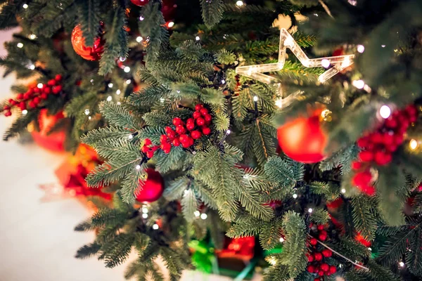 Kerst achtergrond boom New Yeae tak met decoraties rode ballen geschenken en ster, met bokeh licht — Stockfoto