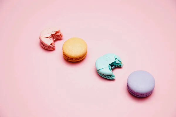 Turquesa colorida, rosa, laranja, bolo roxo Macaron francês ou macaroon mordido em fundo rosa — Fotografia de Stock