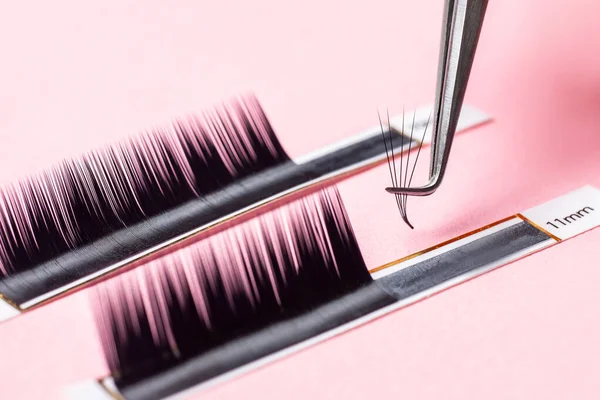 Procedimiento de extensión de pestañas. Conjunto de pestañas macro foto, fondo rosa —  Fotos de Stock