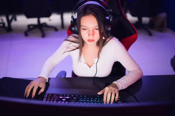 Streamer hermosa chica jugador profesional jugando juegos en línea ordenador con auriculares, color rojo y azul — Foto de Stock