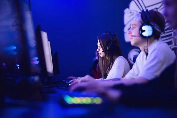 Командный профессиональный геймер, играющий в турниры онлайн игры компьютер с наушниками, красный и синий — стоковое фото
