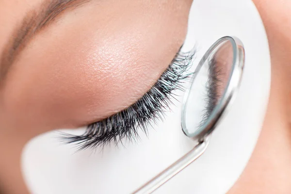 Eyelashes extensions procedure in spa beauty salon. Macro Beautiful eye with makeup