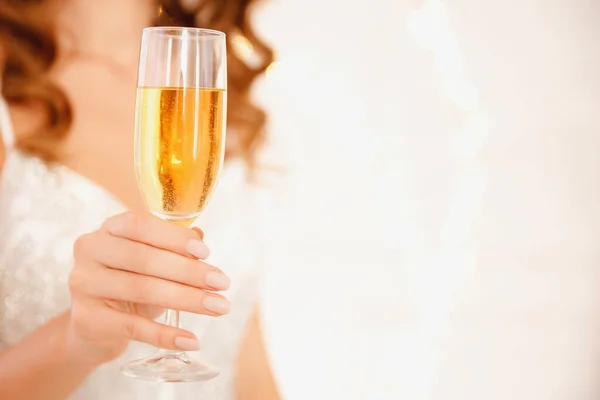 Szklanka musującego szampana w rękach dziewczyny z manicure, zamazane tło. Koncepcja świąt Bożego Narodzenia i strony, przestrzeń do kopiowania — Zdjęcie stockowe