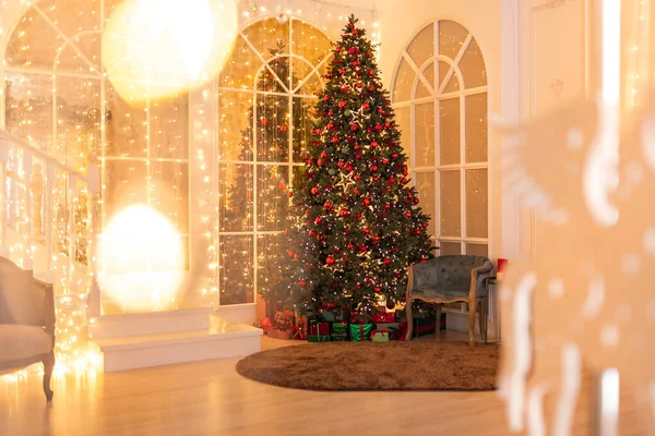 Binnenste kerstboom versierd met rode ballen, sterren, verlichting, geschenken liggen hieronder — Stockfoto