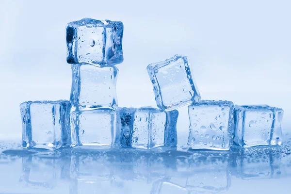 Cubos de hielo cuadrados con gotas de agua limpia sobre fondo azul —  Fotos de Stock