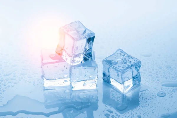 Cubos de hielo cuadrados con gotas de agua limpia sobre fondo azul con luz solar —  Fotos de Stock