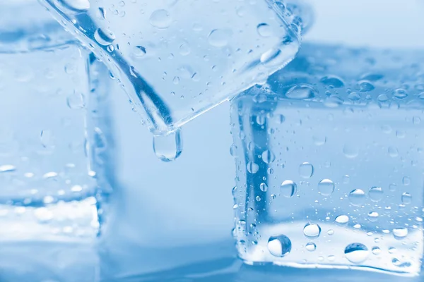 Cubos de gelo macro quadrado com gotas de água limpa no fundo azul — Fotografia de Stock