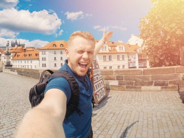 Genç adam sırt çantalı turistin Prag, Çek Cumhuriyeti 'nde fotoğraf makinesi Charles Bridge' i çekmesinden memnun. Seyahat kavramı