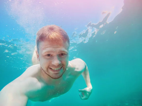 Man under water in turquoise sea. concept of pain from bite jellyfish — Stock Photo, Image