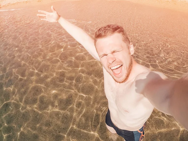 Heureux touriste masculin sur la plage près de la mer en France. Sourire, prendre des photos selfie sur la caméra d'action — Photo