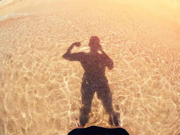 L'uomo pompato muscoli rende ombre silhouette selfie dal sole su sabbia dorata e mare. Preparazione concettuale per l'estate — Foto Stock